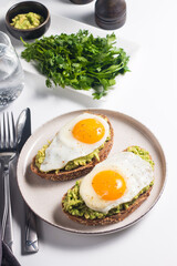 Avocado egg sandwich with a glass of water. Healthy light breakfast concept. Whole grain toasts with mashed avocado and fried eggs