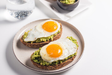 Avocado egg sandwich with a glass of water. Healthy light breakfast concept. Whole grain toasts...
