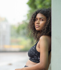 Young woman standing, confident looking, portrait. A beautiful African American person has attractive curly afro hair. Modern multi-ethnic girl enjoy carefree relaxing outside with cool posing