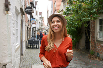 Smiling tourist woman strolling in Schnoor neighborhood, Bremen, Germany - obrazy, fototapety, plakaty