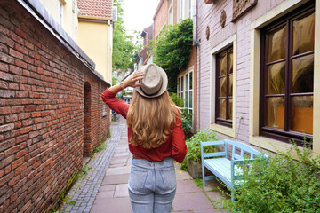 Beautiful tourist girl strolling in Schnoor neighborhood, Bremen, Germany - obrazy, fototapety, plakaty