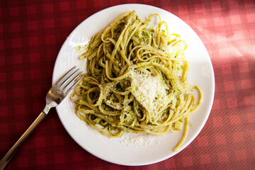 closeup of a plate with spaghetti with pesto on a set table