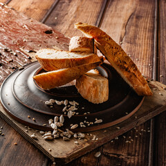 Homemade cakes, sliced ​​baguette, white bread with seeds and sesame seeds, golden crust, elements of wood and ceramics
