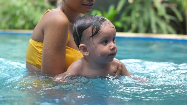 The mother teaches the child to swim, so that the child learns to stay on the water and in all likelihood the child likes the teaching. The child is happy and behaves calmly, is not afraid of water.