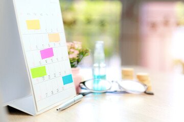 Close up business desk calendar with paper notes and office equipment concept of event planner or personal organization reminder and schedule or planning.