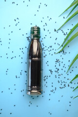 Black Cumin seeds and oils in a container on blue background 