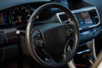 Fototapeta na wymiar Black luxury modern car interior. Steering wheel, speedometer, display, and multimedia dashboard. Detail of car interior inside.