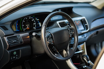 Black luxury modern car interior. Steering wheel, shift lever, speedometer, display, gearbox handle, and multimedia dashboard. Detail of car interior inside. Automatic gear stick.