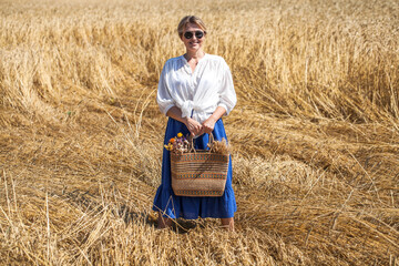 Naklejka na ściany i meble Portrait of a beautiful woman in a wheat field