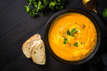 Pumpkin soup puree with cream at black background. Top view with copy space.