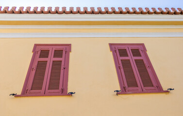 House facade with wood window and yellow wall in Athens, Greece