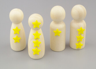 Rating and ranking people concept. Wooden people figures with different amount of stars on gray...