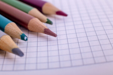colored pencils and a notebook in a cage. school supplies. school. wooden pencils.