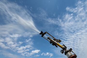 künstliche Bewässerung in der Landwirtschaft, Wasserdosierung und Strahlrohr vor blauem Himmel.