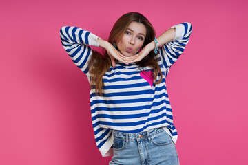 Playful young woman making a face while standing against colored background