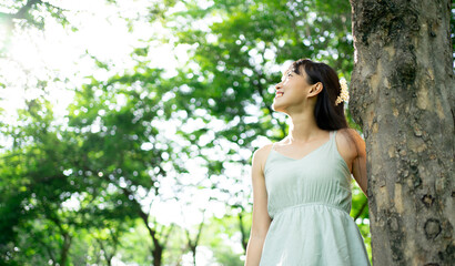 Beautiful young woman relaxing at park during summer season with closed eyes. Happy free natural...