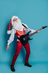 Full size of Cool Santa Claus who stands with electric guitar on blue background. Christmas party.
