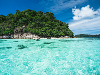 Scenic view of Koh Dong Island breathtaking crystal clear turquoise sea water with coral reef transparent against summer blue sky. Near Koh Lipe Island, Tarutao National Marine Park, Satun, Thailand.