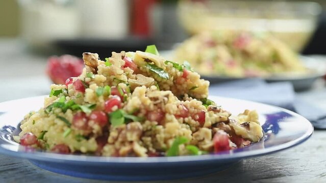 Eating of couscous salad with pomegranate.
