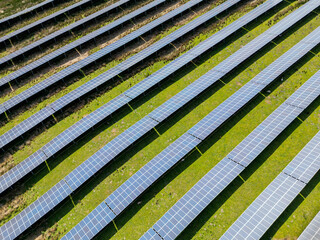 Aerial view of rows of solar panels instaked in a farm field. No people.