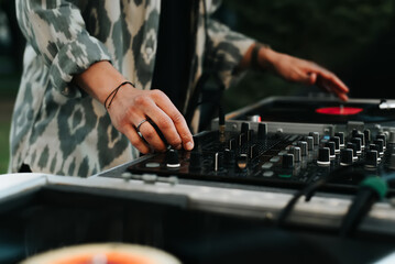 DJ mixes vinyl records on turntable, plays music at street festival in evening, outdoors. Close-up, selective focus