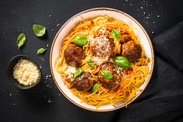 Pasta with Meatballs in tomato sauce on dark stone table. Traditional italian dish. Top view with copy space.
