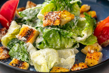 Caesar salad is a green salad of romaine lettuce and croutons dressed with mustard, Parmesan cheese, and garlic bread.