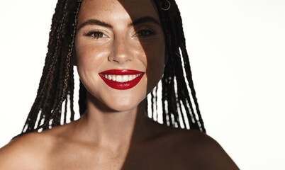 Beautiful smiling fashion model, woman with red lipstick and white smile, has shadow on half of...
