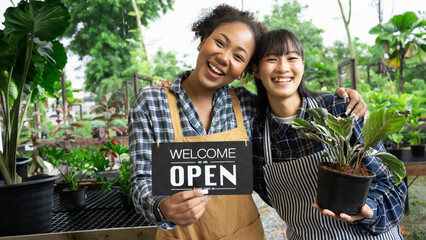 Portrait of mixed-races beautiful women partner owner standing in own tree shop and smiling to camera. Asian and African American females business partners working garden store. Business concept.