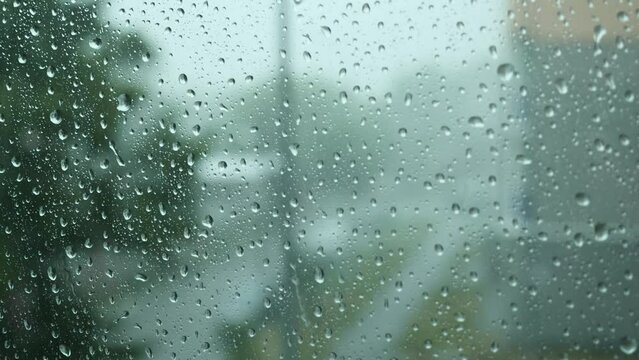 Close-up of Water Drops on Glass of Window. Drops Roll Down During Heavy Summer Rain. Thunderstorm with Strong Gusts of Wind. 4K.