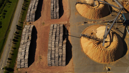 Aerial top-down shot over piles of trunks and sawdust mountains in paper mill factory. Fray Bentos...