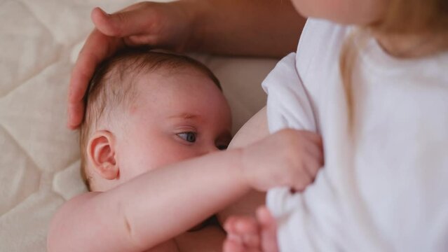 Woman breastfeeding newborn baby. Mother breastfeeding newborn boy lying in bed. Concept breast feeding. Baby eating mother's milk. Young woman nursing and feeding baby. Concept of lactation infant.