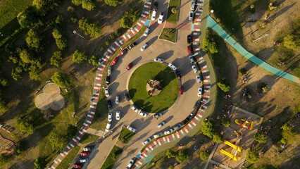 Fototapeta premium Aerial top down view of traffic crossing intersection and cars parked along road side.