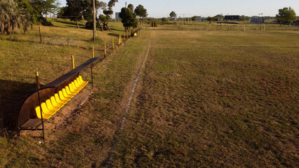 Aerial shot of empty yellow substitute bank at sunset on amateur soccer football field