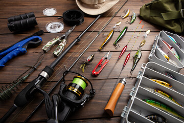Fishing tackle - fishing spinning rod, hooks and lures on wooden background. Active hobby...