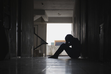 Silhouette of a depressed man sitting sadly in front of a room or corridor Concept Sad man Economic poison Plague Cry Drama Lonely and unhappy concept.