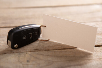 Car insurance or rent concept. Vehicle security key with blank tag on the wooden background