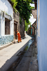 Street sweeper in orange uniform sweeping the street in the colonial Getsemani neighborhood in...