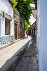 Street sweeper in orange uniform sweeping the street in the colonial Getsemani neighborhood in...