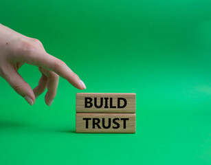 Build trust symbol. Wooden blocks with words Build trust. Beautiful green background. Businessman hand. Business and Build trust concept. Copy space.