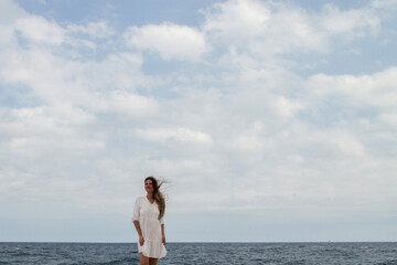 Fototapeta na wymiar Girl with flowing hair against the background of the sea and the sky. Girl in a white dress. appeasement. Sea. Ocean.