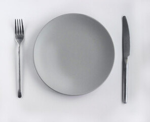 Grey empty plate with silver cutlery on the white table