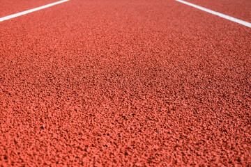 Sports stadium with red artificial rubber ground running tracks and white lines on it
