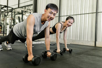 exercise concept The female and male members of the gym doing the basic renegade row posture with dumbbells while looing at each other’s face