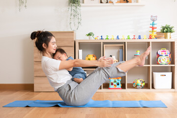 Fototapeta na wymiar Asian mom doing yoga exercise balance body with adorable infant baby on yoga mat smiling and happiness at home. Relax time. Baby and Mother day