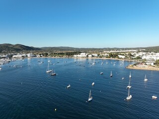 Obraz premium Aerial view of the coast of an island, full of boats and sailboats anchored off the beach.