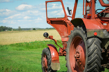 Obraz premium Red tractor in the fields is waiting for harvester 