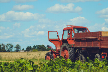 Red tractor in the fields is waiting for harvester 