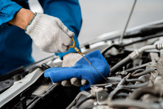 Close-up, a car mechanic checking the oil in a car's engine. Technician inspecting and maintaining the engine of a car or vehicle. Female car mechanic checking car engine - Powered by Adobe