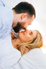 Happy young couple lying on a bed, husband kissing wife and hug. 